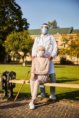 Fototapeta premium Medical specialist standing behind a senior citizen on a bench