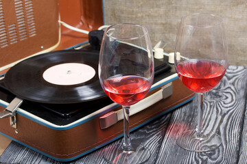 Old turntable. Nearby are two glasses of alcohol. Retro party equipment.