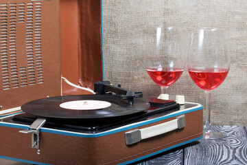 Old turntable. Nearby are two glasses of alcohol. Retro party equipment.