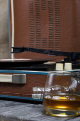 Old turntable. Nearby is a glass of strong alcohol. Retro party equipment.