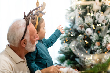 Youngster in arms of his grandfather enjoying Christmas time