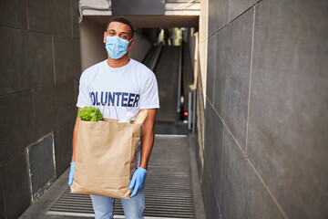 Glad volunteer in a face mask with a paper bag