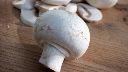 Fluffy bright white mushroom in great close up on wooden cutting board. Spectacular details are visible in this isolated macro photo of the mushroom. Food and culinary concept.