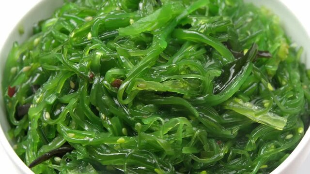 Rotating bowl with tasty seaweed salad, closeup