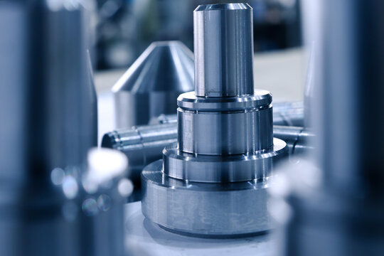 Iron parts machined on a CNC lathe close-up. Metalworking parts in the manufacture of CNC machine tools. Shiny metal parts made at the factory, lie on a table.	