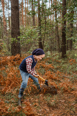 Little boy in the autumn forest. A boy with an ax near a tree. Woodcutter hold ax. Standing in the forest with axe.
