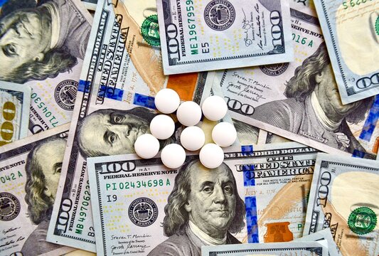 USA national currency, top view of mixed American dollars banknotes with white pills on it, drugs, money laundering, cartel, expensive medicine concepts. Top view