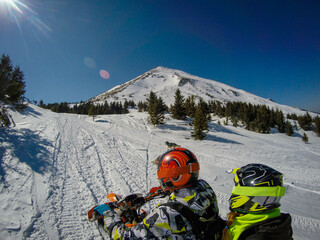 Girl and boyfriend ride in the mountains on a snowbike. Their husky dog ​​runs with them. Hike...