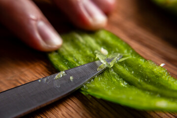 Hands unveiling a serrano pepper with a knife to prepare a mexican dish. Close up.