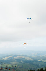A man is flying on a paraglider in clouds and fog. Summer sports, active lifestyle, activity in...