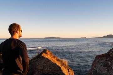 Young man standing on the shore and admiring the famous rock of Percé in the horizon