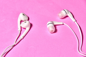 Two types of headphones on pink-lilac background
