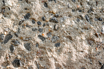 Detail of surface texture with small pebble rock on dirty ground. sun glare