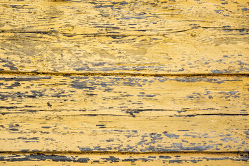 Grunge background from weathered yellow wooden plank. cracks in old yellow paint. wallpaper or background