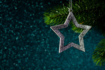 silver star on a Christmas tree branch on a blue shining background from bokeh, mock up.