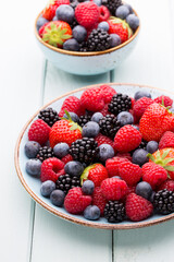 Fresh berry salad on blue dishes. Vintage wooden background.