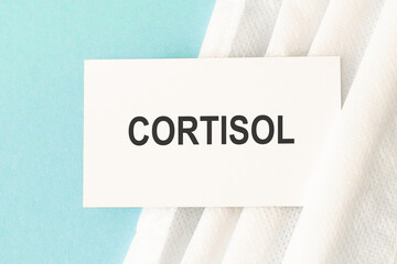 Word cortisol with medical mask on a blue background.