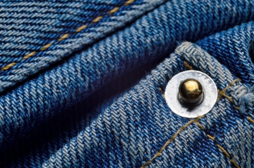 metal button on the pocket of blue jeans. close-up.