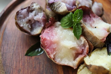 Multi-colored baked potatoes on a wooden surface.
