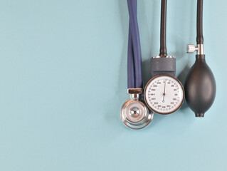 Acoustic stethoscope head, pressure gauge and blower hanging from above and isolated on blue...