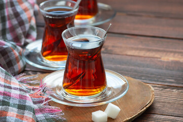 Glass cup of brewed black turkish tea on wooden table, traditional hot drink concept