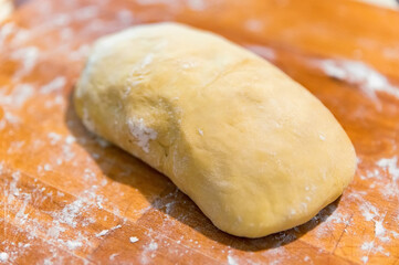 Raw dough covered with flour on a wooden cutting board