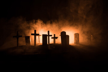 Fototapeta na wymiar Scary view of zombies at cemetery dead tree, moon, church and spooky cloudy sky with fog, Horror Halloween concept with glowing pumpkin. Selective focus
