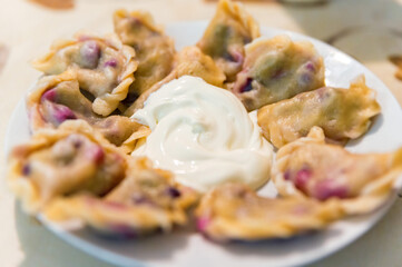 Dumplings with cherry and fork on the plate closeup.