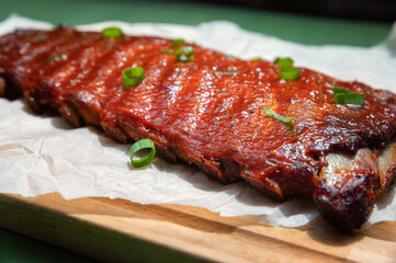 Close up board with pork ribs grilled with BBQ sauce, peanuts and jalapeno