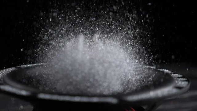 Trembling loudspeaker throwing silver flour in the air. Super slow motion close-up shot.