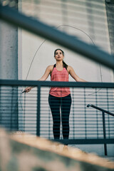 Fit sportswoman skipping the rope and warming up outdoors.