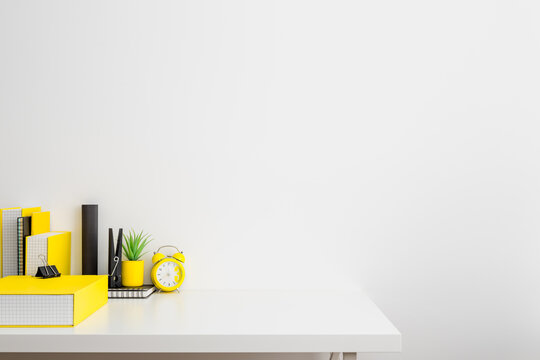 Creative desk with a blank picture frame or poster, desk objects, office supplies, books, alarm clock and plant on a white background.	
