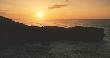 Rock wall silhouette at sea bay sunset aerial view. Tropical wild nature seascape at sun set light. Picturesque scape at Sumba island ocean shore, Indonesia, Asia. Cinematic soft shot
