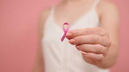 Pnk october, brest cancer awareness ribbon in the hand of a young unrecognzable woman. High quality...