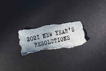 2021 New Year's Resolutions - text on torn paper on dark desk in sunlight