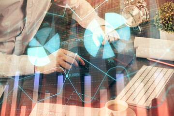 Double exposure of man's hands holding and using a phone and financial graph drawing. Analysis concept.