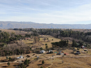 Vista a&eacute;rea de algunas casas con monta&ntilde;as al fondo, en las afueras de un pueblo.
