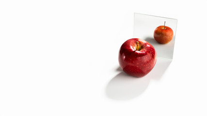Red apple on a white background looks in the mirror