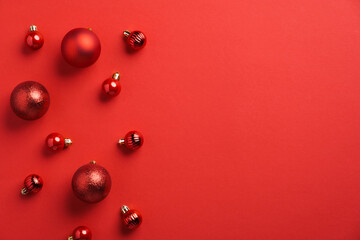 Red Christmas baubles decoration on red background. Flat lay, top view, copy space. New Year greeting card mockup, banner template. Minimal, elegant style.