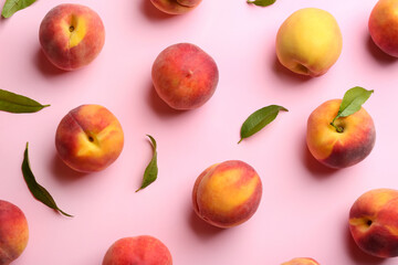 Fresh ripe peaches and green leaves on pink background, flat lay