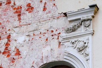 Fragment of facade with ruined stucco fretwork of an old abandoned building.