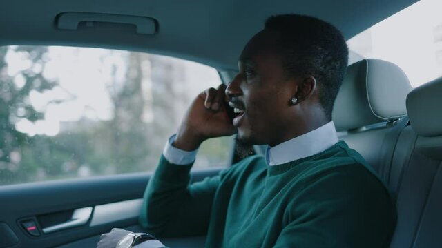 Happy Stylish Young African American Man Speak On Smartphone Smiling Sitting In Car At Backseat At Sunlight . Funny Businessman. Communication Passenger Worker. Slow Motion