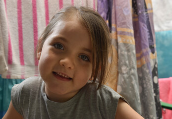 HERMOSA NI&Ntilde;A COLOMBIANA DE OJOS CLAROS SONRIENDO. FONDO DE SABANAS DE COLORES COLGANDO