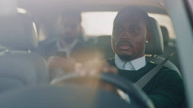 Close up handsome taxi driver african american man driving car with passenger. Serious man at sunlight. Automobile businessman traffic transportation. Slow motion