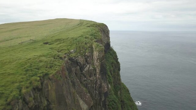 Green cliffs of farroe islands in cloudy weather. Drone aerial view.