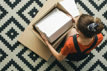 Caucasian woman at home opening carton box, just delivered parcel on address