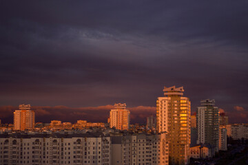 Fototapeta premium big city residential houses with sunset warm light and dark clouds