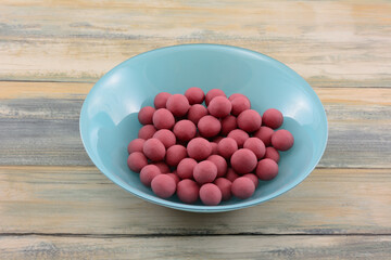 Blueberries dipped in ruby cacao chocolate in blue bowl on table