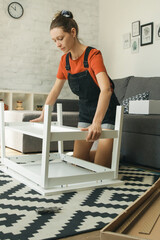 Fototapeta na wymiar Caucasian woman at home assembling furniture by herself