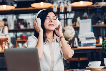 Lifestyle freelance woman he using earphones listening music during working on laptop computer in coffee shop